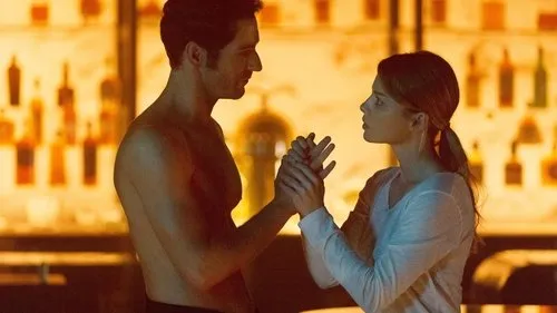 Lucifer – T01E04:Novidades masculinas 1 Homem sem camisa e mulher de camisa clara,de mãos dadas,se olham intensamente em um bar com iluminação quente.