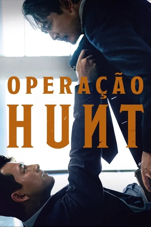 Dois homens em ternos;um em pé aponta arma para o outro caído,que o encara. Atmosfera de suspense e confronto.