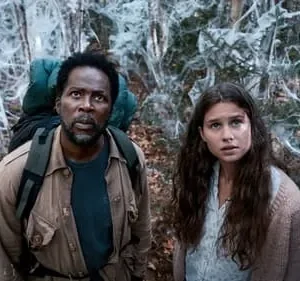 Homem e mulher assustados em floresta sombria, coberta por densas teias brancas. Clima de suspense/terror.