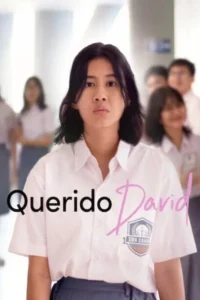 Uma jovem estudante de uniforme escolar branco e cabelo escuro encara com seriedade. Colegas desfocados num corredor escolar.