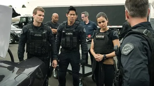 S.W.A.T.:Força de Intervenção – T01E09:Pontos Cegos 1 Quatro policiais LAPD SWAT,três homens e uma mulher,em uniformes táticos escuros,se reúnem ao ar livre com veículos.
