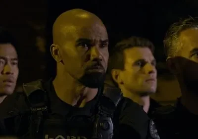 Quatro homens sérios em coletes táticos, olhando à frente na escuridão noturna. Clima intenso e vigilante.