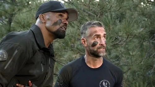 Dois homens vigilantes com pintura de camuflagem olham para cima em uma floresta. Um de boné e uniforme tático,o outro de camiseta.