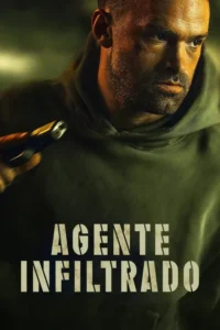 Homem barbudo, sério, com capuz verde e marcas no rosto, segura uma pistola. Fundo escuro e tenso.