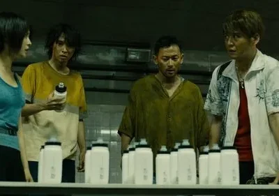 Quatro personagens (3 homens, 1 mulher) com expressões tensas olham garrafas em sala industrial escura. Clima de desafio.