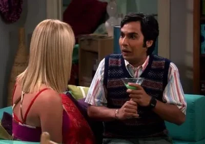 Homem de colete e camisa listrada, segurando um drink verde, olha surpreso para mulher loira de costas. Sala colorida.