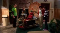 Quatro homens curiosos em um apartamento observam uma máquina do tempo steampunk com assento vermelho e grande relógio.