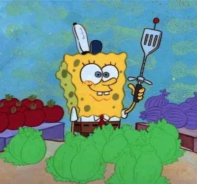 Personagem esponja amarela sorrindo, segurando uma espátula como espada num mercado com vegetais coloridos.