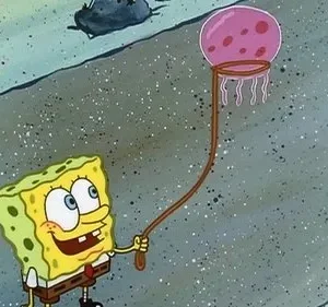 Um personagem quadrado amarelo sorri, segurando uma rede com uma água-viva rosa sobre fundo marinho.