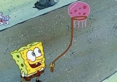 Um personagem quadrado amarelo sorri, segurando uma rede com uma água-viva rosa sobre fundo marinho.