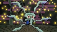 Polvo azul de olhos vermelhos e tentáculos esticados numa sala escura com luzes amarelas cintilantes. Ele parece sobrecarregado.