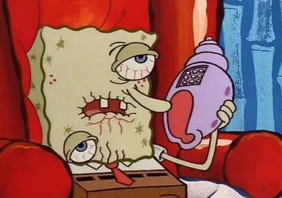 Personagem esponjoso doente, olhos vermelhos, dentes quebrados, atende telefone concha. Sentado em poltrona vermelha, parece exausto.