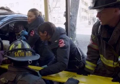 Profissionais de resgate atendem uma vítima em um carro acidentado. Bombeiros e paramédicos em cena de emergência urbana.