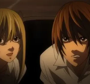 Duas figuras de anime em close-up, ambiente escuro. Mulher loira com sorriso tenso; homem de cabelo castanho com olhar sério e focado. Clima intenso.