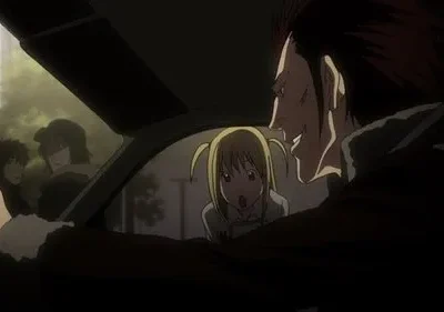 Homem ruivo sorrindo maliciosamente ao lado de mulher loira assustada em carro. Pessoas observam no fundo. Clima tenso.