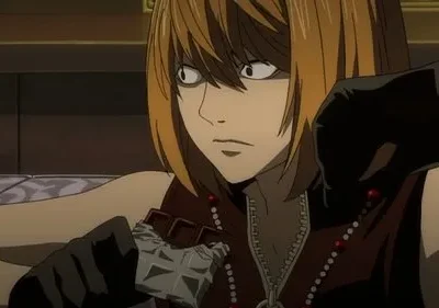 Anime: Jovem de cabelo loiro e olhos arregalados, vestindo luvas pretas, segura um chocolate com expressão intensa.