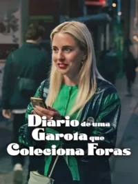 Uma mulher loira sorri, segurando um celular numa rua movimentada à noite. Veste camisa verde e jaqueta escura. Clima urbano.