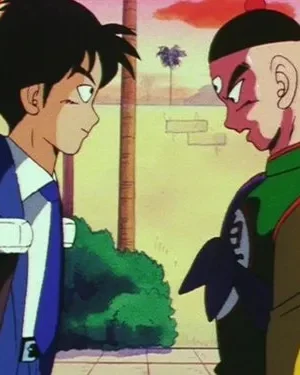 Um jovem de terno azul e um homem com terceiro olho e traje colorido se encaram intensamente em cenário externo.