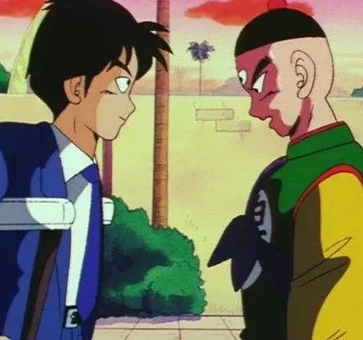 Um jovem de terno azul e um homem com terceiro olho e traje colorido se encaram intensamente em cenário externo.