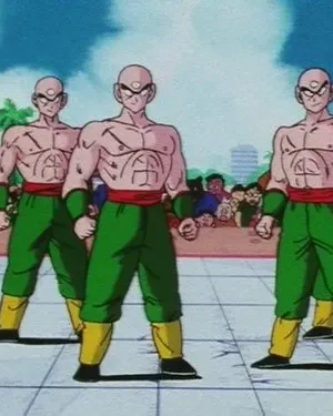 Cinco guerreiros musculosos e carecas, com três olhos, vestindo verde e vermelho, estão em um ringue de luta, com público ao fundo.