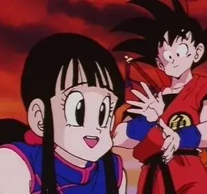 Anime: Menina sorridente de cabelo escuro e menino de cabelo espetado em frente a um pôr do sol dramático de tons vermelhos e laranjas.