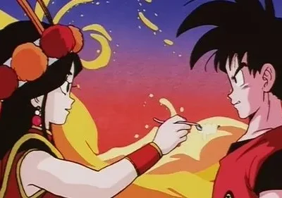 Mulher de cabelo escuro longo e cocar colorido alimenta homem de cabelo espetado com uma colher. Fundo vibrante em tons de pôr do sol.