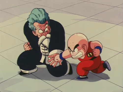 Dragon Ball – T01E24:O Ataque Furioso de Kuririn 1 Um velho de cabelo azul e barba,agachado,e um menino careca com kimono laranja,socando. Ambos com expressões intensas e foco na luta.