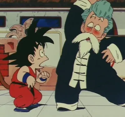 Um menino de gi vermelho com cauda observa chocado um mestre idoso de barba e cabelo azul, que faz uma pose de luta corada e desajeitada.