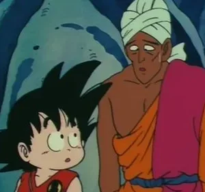 Menino de cabelo espetado olhando curioso e homem de turbante e robe colorido, com expressão cansada. Cenário rochoso azulado escuro.