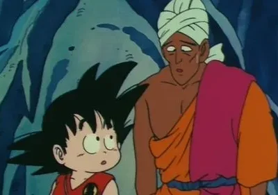 Menino de cabelo espetado olhando curioso e homem de turbante e robe colorido, com expressão cansada. Cenário rochoso azulado escuro.