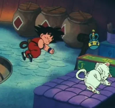 Menino de cabelo preto espetado e cauda, de roupa vermelha, dorme no chão. Um gato branco dorme num colchão roxo. Ambiente tranquilo.