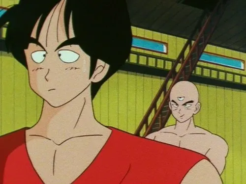 Dragon Ball – T01E87:Yamcha Contra Tenshinhan 1 Dois homens em estilo anime. Um jovem com camisa vermelha parece preocupado. Atrás,um careca de três olhos e musculoso sorri confiante.