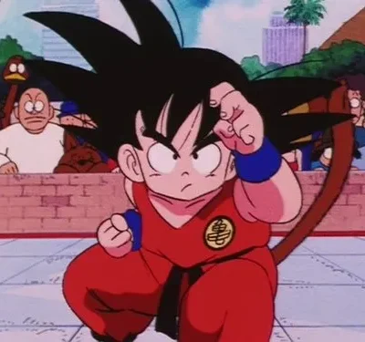 Jovem de cabelo espetado, gi vermelho e cauda, em pose de luta numa arena. Vários espectadores assistem ao fundo. Clima de ação.