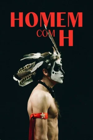 Pessoa sem camisa, de perfil, com pintura facial dramática e cocar de penas. Braçadeira vermelha em fundo preto.