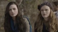 Pôster: Duas jovens ao ar livre. Uma com cabelo escuro e cachecol azul; a outra ruiva com gorro. Ambas com expressão séria e atenta.