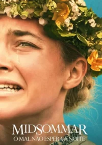 Close-up de mulher loira chorando, usando uma coroa de flores coloridas contra céu azul claro. Expressão de angústia.
