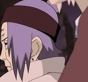 Perfil de mulher com cabelo roxo, bandana marrom e cicatrizes na testa. Expressão séria. Parte de outra pessoa em primeiro plano.