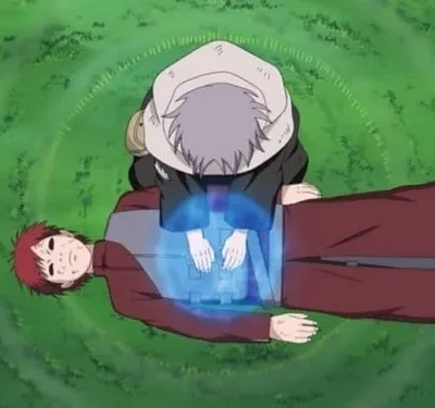 Jovem de capuz cinza ajoelhado sobre outro de cabelo vermelho com marcas no rosto, aplicando energia azul no peito em gramado verde.