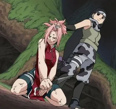 Duas ninjas em confronto na floresta. Uma de cabelo rosa, ferida e ajoelhada, é segurada pelos cabelos pela outra.