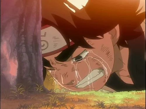 Um jovem de anime com faixa na cabeça chora em agonia no chão,rosto com arranhões. Está encostado numa árvore,sob luz quente de pôr do sol.