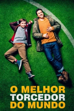 Pai e filho sorridentes deitados na grama verde de um campo de futebol, com o menino apontando. Clima feliz e descontraído.