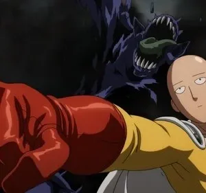 Herói careca de traje amarelo e luva vermelha estende o punho com expressão entediada, contra um monstro sombrio e dentuço.