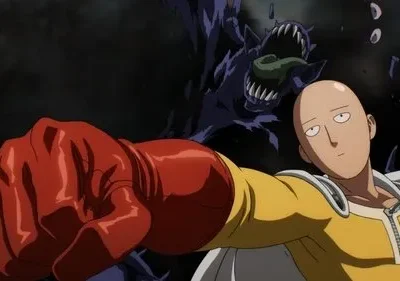 Herói careca de traje amarelo e luva vermelha estende o punho com expressão entediada, contra um monstro sombrio e dentuço.