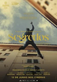 Homem borrado em salto ou queda contra céu nublado e prédios. Cores desbotadas criam atmosfera dramática e introspectiva.