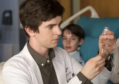 Jovem médico em jaleco branco examina um frasco, com menino paciente na cama de hospital observando-o.