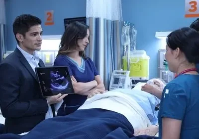 Médicos e enfermeiras cercam paciente idoso em hospital. Um médico de terno mostra exame de ultrassom em tablet, com ar sério.