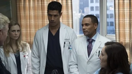 The Good Doctor:O Bom Doutor – T01E16:Dor 1 Grupo de médicos e um paciente em hospital. Três profissionais de jaleco com expressões sérias. Janela urbana ao fundo.