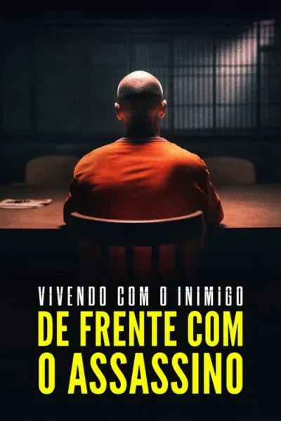 Pessoa careca de camisa laranja, vista de costas, sentada em sala escura com mesa e janela gradeada. Clima sombrio.