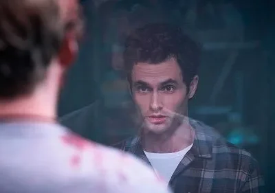 Homem de cabelo escuro e camisa xadrez olha fixamente pessoa de costas com sangue na roupa. Um vidro os separa, gerando tensão.