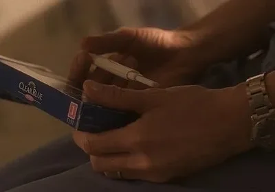 Mãos de uma pessoa seguram um teste de gravidez e sua caixa. Luz baixa cria uma atmosfera tensa e íntima de grande expectativa.